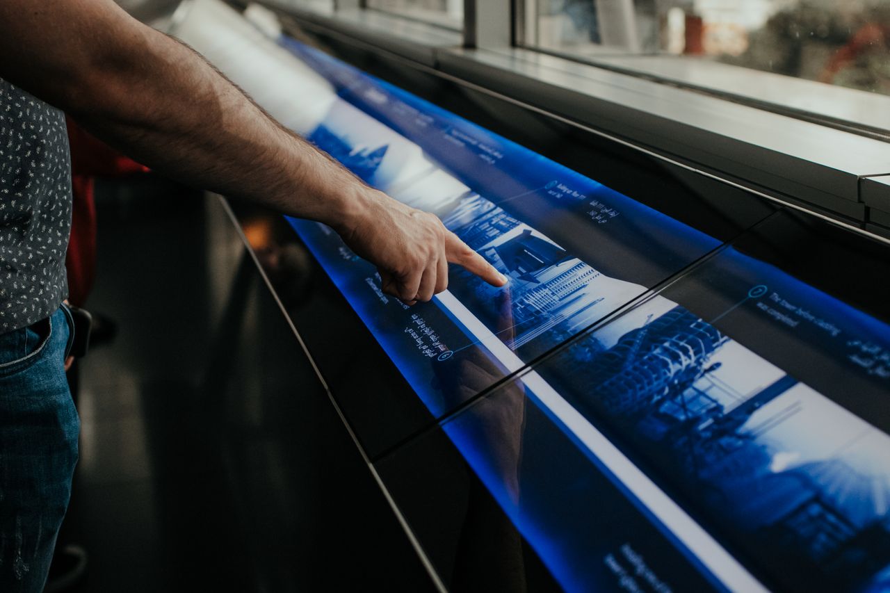 Close-up of a person interacting with a touchscreen display in a modern environment.