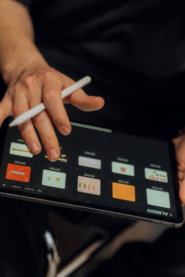 A person working on a digital tablet with a stylus, creating designs using an application.